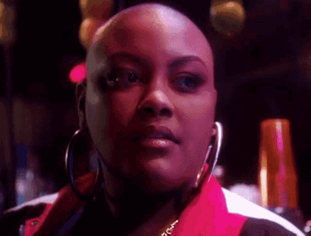 a close up of a woman 's face with a bald head and hoop earrings