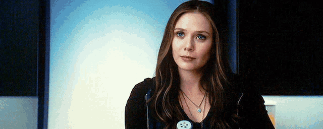 a close up of a woman wearing a black shirt and a necklace with a button on it .
