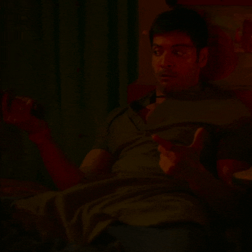 a man is laying on a bed in a dark room and talking on a phone .