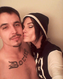 a woman kisses a shirtless man with a tattoo of the name borico on his chest