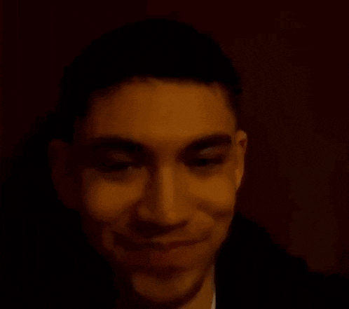 a close up of a man 's face with a smile on his face in a dark room .
