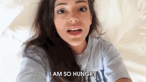 a woman laying on a bed with the words i am so hungry on her face