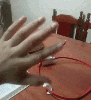 a person 's hand is reaching out towards a red cord on a table .