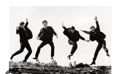 four men in suits are jumping in the air