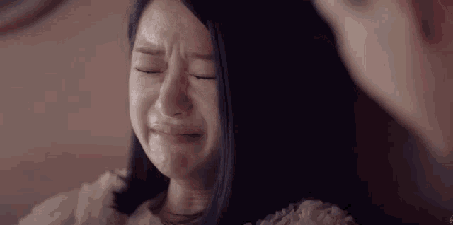 a woman is crying with her eyes closed while a man looks on .