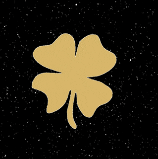 a gold four leaf clover is on a black background surrounded by stars .