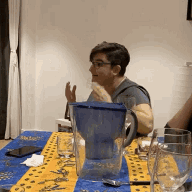 a woman sitting at a table with a pitcher of water on it