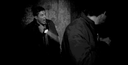 a man is holding a flashlight in a dark room and shouting .