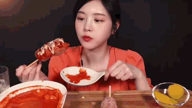 a woman is eating a hot dog with ketchup and mustard on a stick