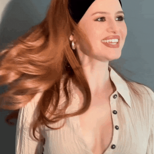 a woman with long red hair wearing a white shirt and a black headband .