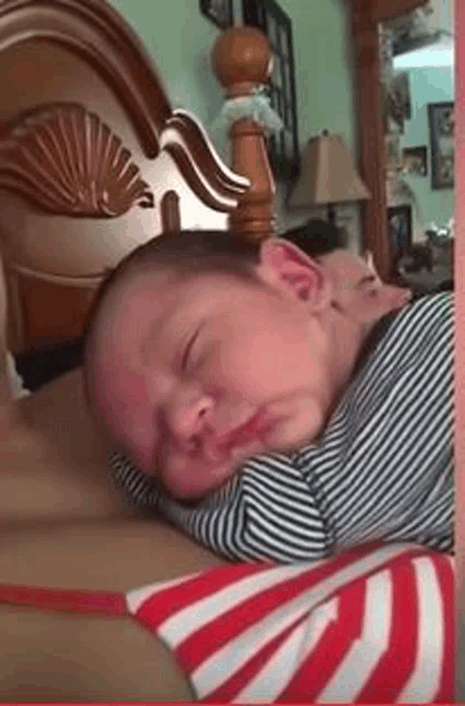 a baby in a striped shirt is sleeping on a woman 's chest .
