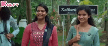 a group of young women are standing next to each other in front of a sign in a park .