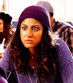 a woman wearing a purple beanie and a purple sweater is making a funny face .