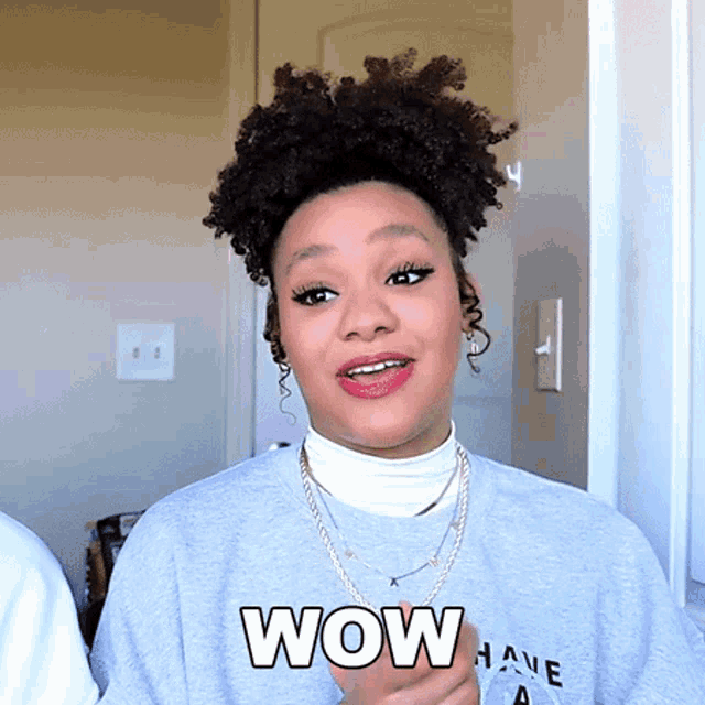 a woman wearing a sweater that says wow has a surprised look on her face