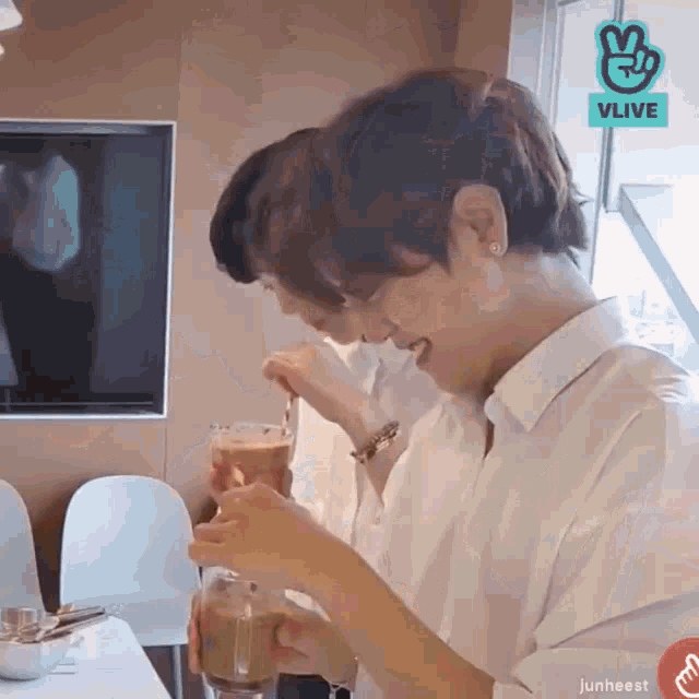 a couple of people sitting at a table with a vlive logo on the bottom right