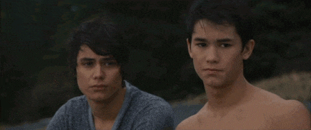 two young men without shirts are sitting next to each other looking at the camera .