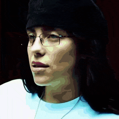 a woman wearing glasses and a black hat looks to the side