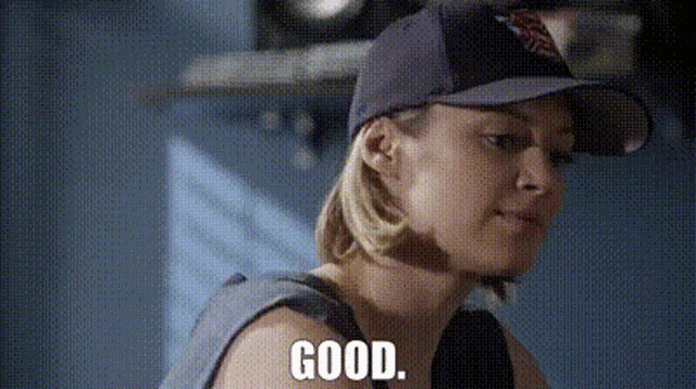 a woman is wearing a baseball cap and says good .