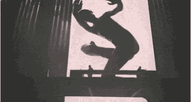 a silhouette of a person jumping in the air with their arms outstretched