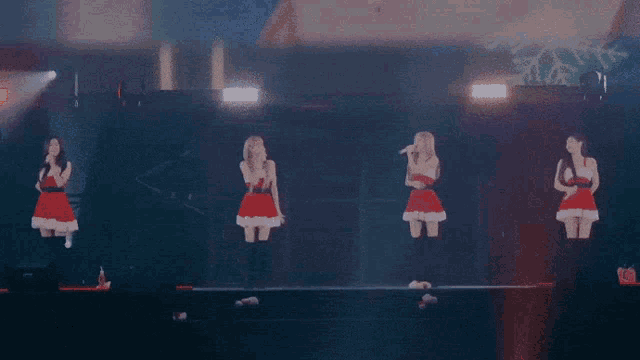 a group of women in santa outfits singing into microphones