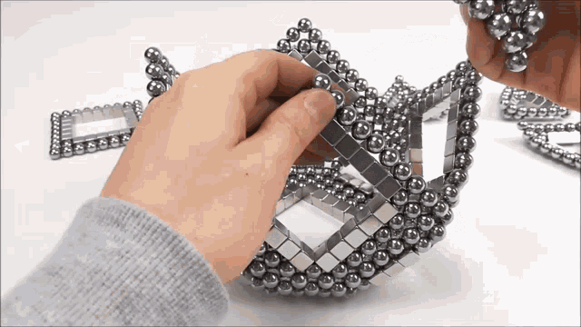 a person is holding a bunch of metal beads in their hands
