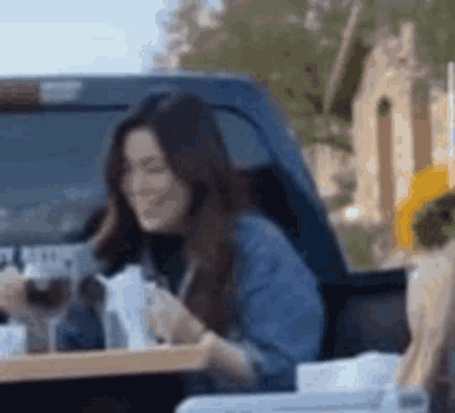 a woman is sitting in the back of a truck eating a sandwich .