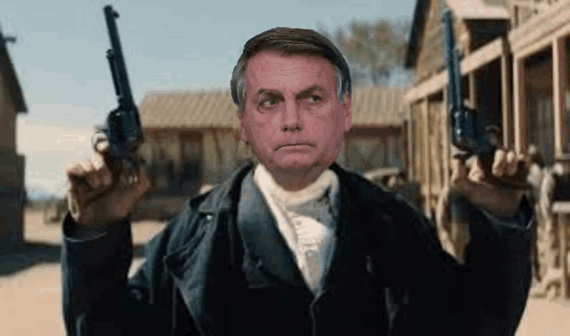a man in a suit is holding two guns in front of a western town .
