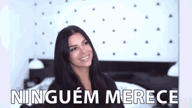 a woman is smiling in front of a bed and the words `` ninguem merece '' are written above her .