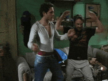 two men are dancing on a couch with one wearing a black shirt that says california
