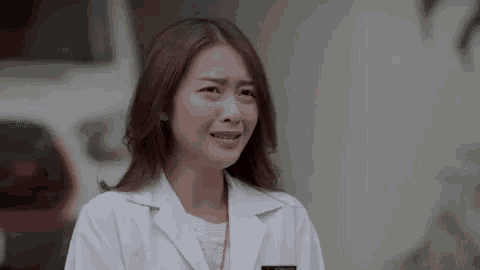 a woman in a white lab coat is making a funny face .