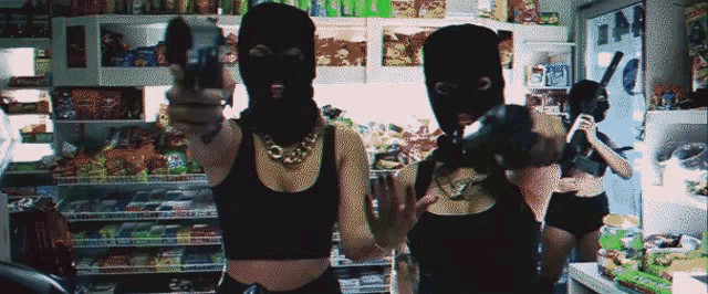 two women wearing ski masks hold guns in a store