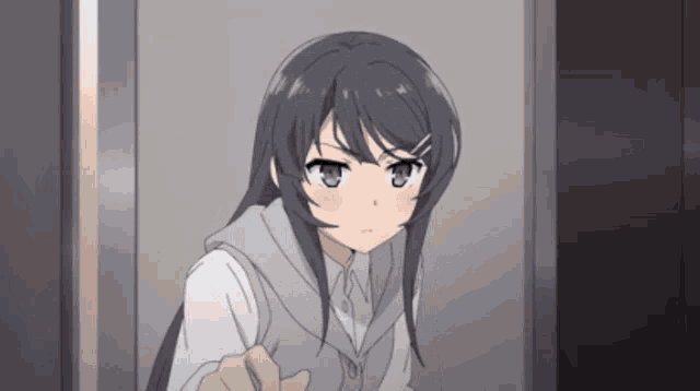 a girl with long black hair is standing in a doorway with a serious look on her face
