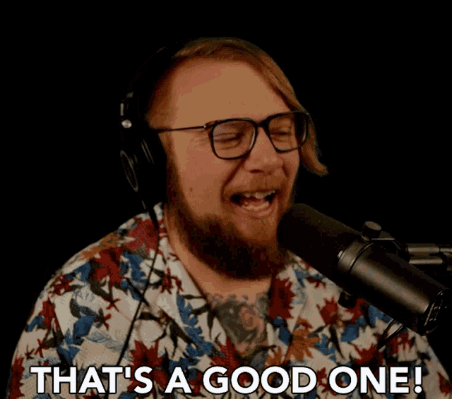 a man singing into a microphone with the words that 's a good one behind him