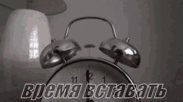 a silver alarm clock is sitting on a table next to a lamp and a lampshade .