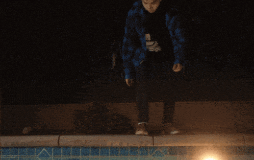 a person sitting on the edge of a swimming pool