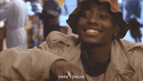 a man wearing a bucket hat is smiling with the name mike tomlin written below him
