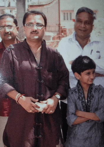 a man with glasses and a mustache is standing next to two other men and a little girl