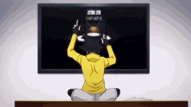 a man in a yellow hoodie is sitting in front of a tv