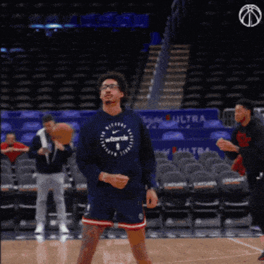 a man wearing a washington wizards sweatshirt is standing on a basketball court