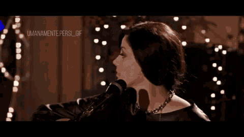 a woman is singing into a microphone while wearing a black leather top .