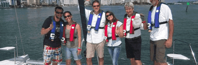 a group of people posing for a picture on a boat wearing life vests