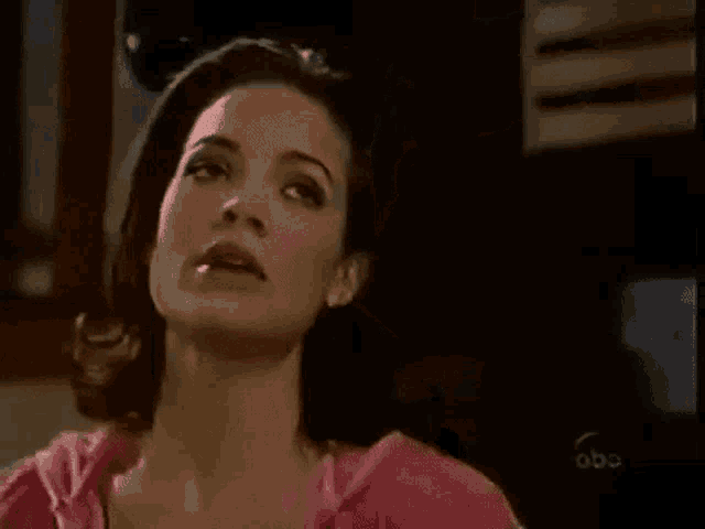 a woman in a pink shirt is sitting in a chair and looking up at the camera .