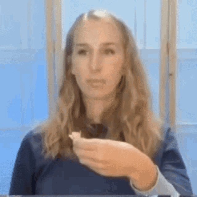 a woman is eating a piece of food in front of a window .