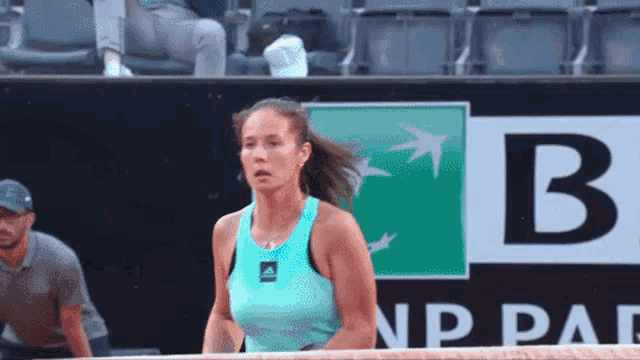 a woman in a blue tank top is standing in front of a bnp paribas sign