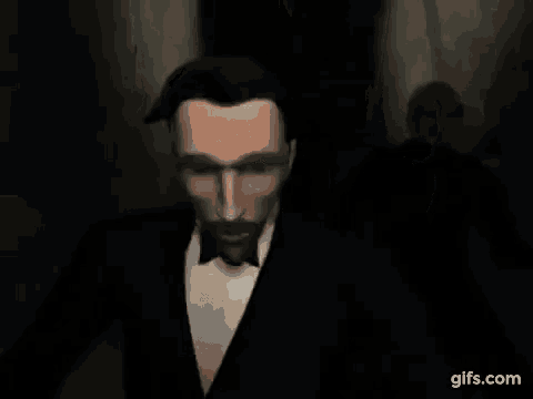 a man in a tuxedo and bow tie is walking through a dark room .