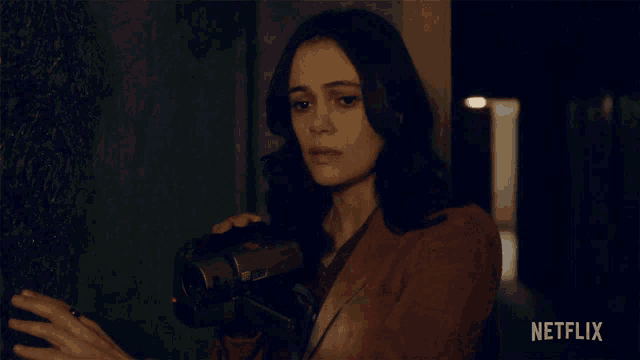 a woman is holding a camera in front of a netflix sign