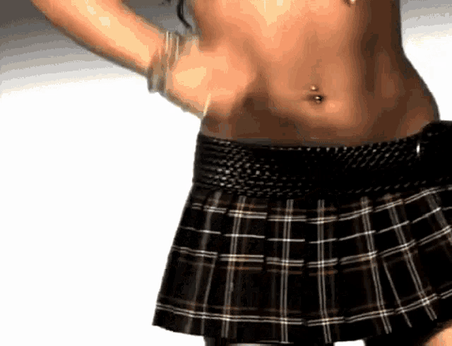 a woman wearing a plaid skirt has a belly button ring