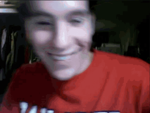 a man wearing a red t-shirt with the word vans on it smiles