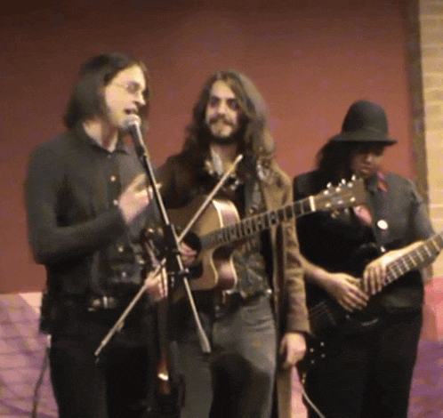 a man singing into a microphone while holding a guitar with the number 13 on it