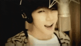 a young man is singing into a microphone in a recording studio .